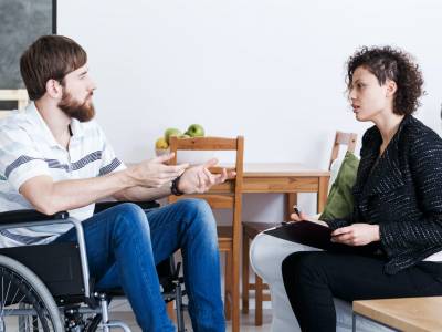 Man in wheelchair talking with psychotherapist